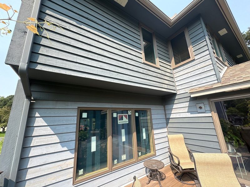 Blue-gray lap siding with a new window above a patio and sunroom
