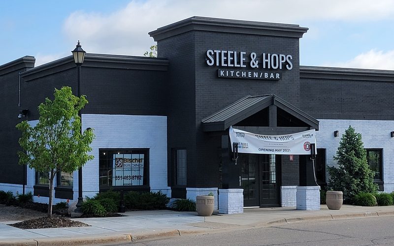 Commercial building exterior with dark painted brick, white-painted lower walls and a gabled entry canopy