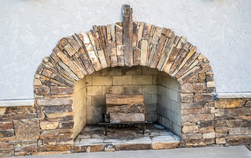 Close-up of a hand-laid stacked-stone fireplace arch with a split-wood firebox