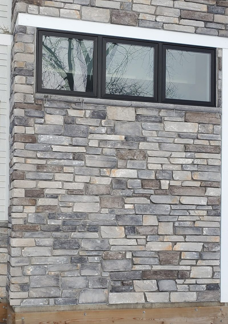 Stacked natural-stone veneer wall in gray and tan tones with white trim