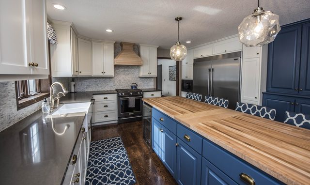 Kitchen with navy lower cabinets, butcher-block island, white uppers and glass pendant lights